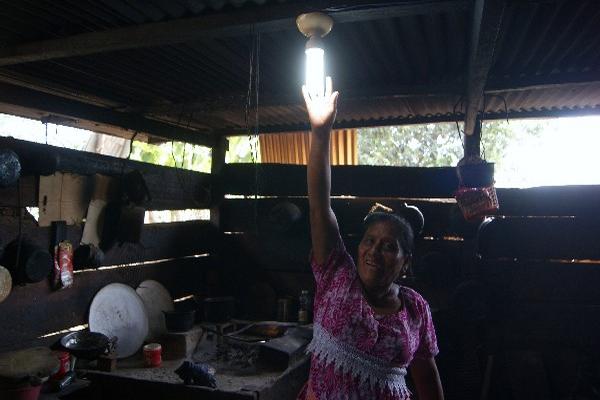 Una mujer muestra una bombilla en su cocina, en la aldea San José lo de Mota, Retalhuleu.