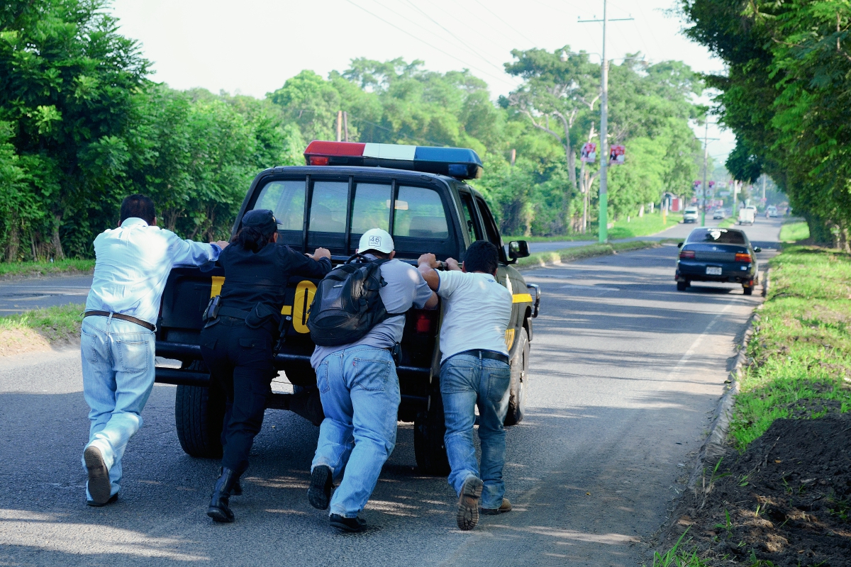 Tres vecinos ayudan a los agentes policiales a empujar el autopatrulla, el cual no podían movilizar por problemas mecánicos, en la cabecera de Retalhuleu. (Foto Prensa Libre: Jorge Tizol)