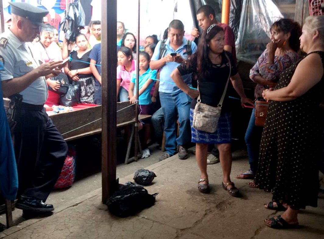 Curiosos observan la bolsa que contiene los restos del recién nacido que dejaron abandonado dentro de una mochila. (Foto Prensa Libre: Hugo Oliva)