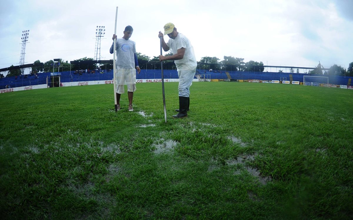 Trabajadores del estadio trabajan para sacar el agua del terreno de juego.