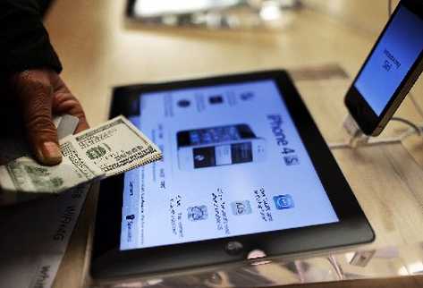 Un consumidor muestra el dinero que usará para efectuar una compra por internet (Foto. AFP)