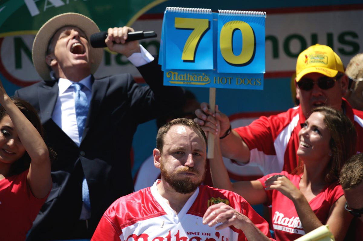 El estadounidense Joey Chestnut engulle un "hotdog", camino de su victoria en el tradicional concurso de comer perritos calientes en Nueva York, Estados Unidos. (Foto Prensa Libre: EFE).