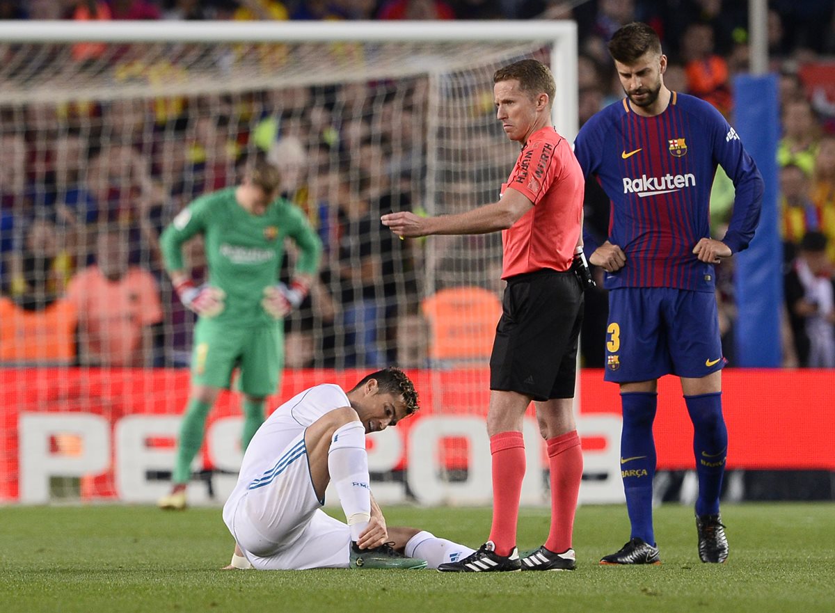Cristiano Ronaldo sostiene su tobillo frente al árbitro Hernández Hernández y Gerard Piqué. (Foto Prensa Libre: AFP)