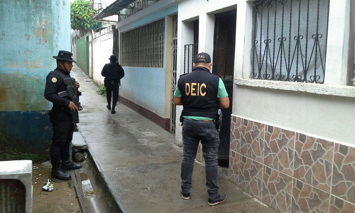 Agentes de la PNC resguardan viviendas allanadas en Zacapa e Izabal, en busca de presuntos integrantes de una banda delincuencial. (Foto Prensa Libre: PNC)