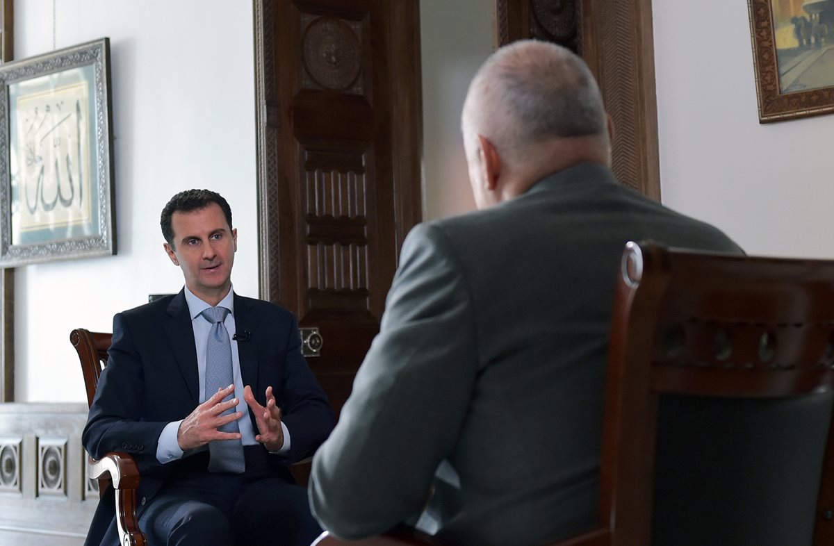 El presidente sirio, Bashar al Asad, (de espaldas), conversa con el periodista de la agencia rusa RIA Novosti. (Foto Prensa Libre: AFP).