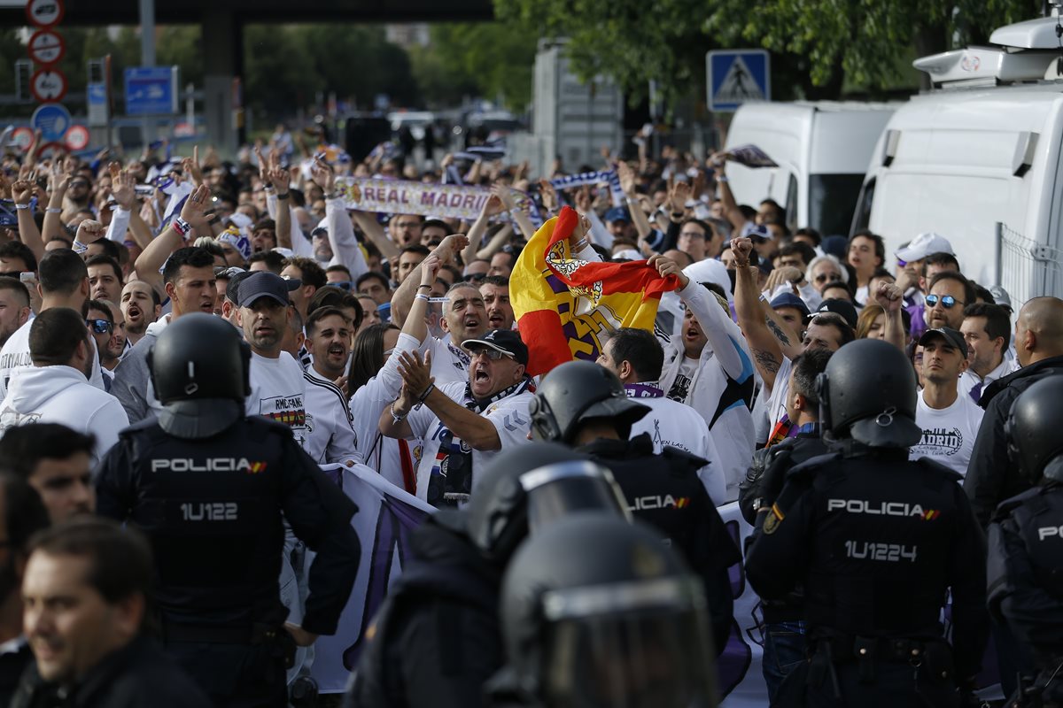 Los aficionados del Real Madrid son resguardados por la seguridad antes de ingresar al estadio.