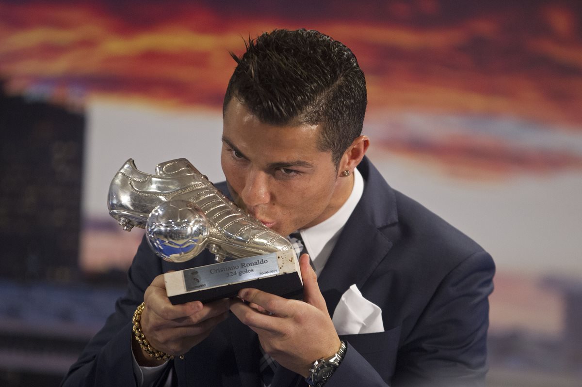 Cristiano Ronaldo besa el trofeo en forma de zapatilla de futbol que recibió como homenaje por igualar a Raúl como máximos goleadores del Real Madrid. (Foto Prensa Libre: AP)