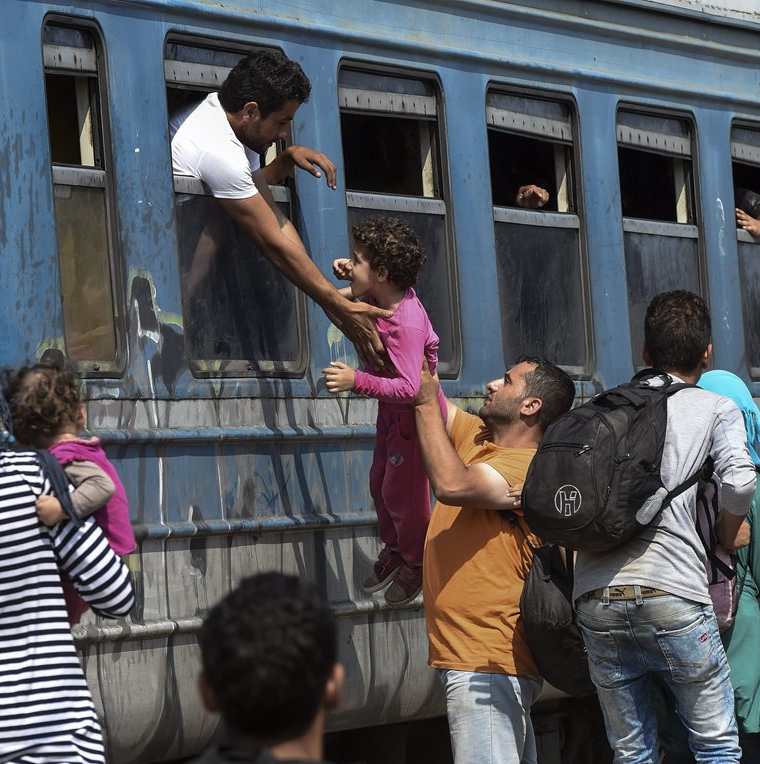 Un hombre trata de subir a un tren por la ventana a una nena. Miles sueñan con llegar a los países industrializados de Europa. (Foto Prensa Libre: EFE).