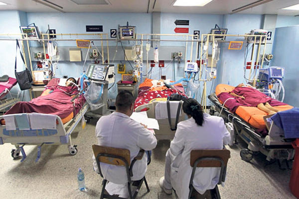Tres pacientes con respiración artificial que deberían recibir cuidados intensivos son atendidos en el área de observación de la sala de urgencias.
