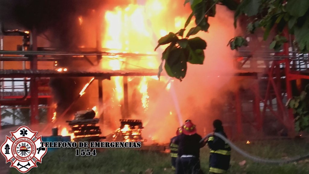Bomberos luchan por sofocar las llamas del incendio que consumió la bodega de una fábrica de pintura en Masagua, Escuintla. (Foto Prensa Libre: cortesía de Bomberos Municipales Departamentales)