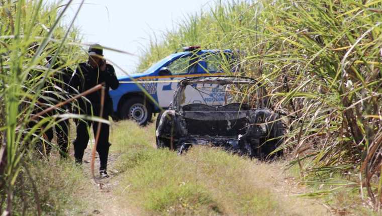 La Policía Nacional Civil inspecciona el lugar donde hallaron un automóvil carbonizado, en ruta a Puerto Quetzal, Escuintla. (Foto Prensa Libre: Redacción)