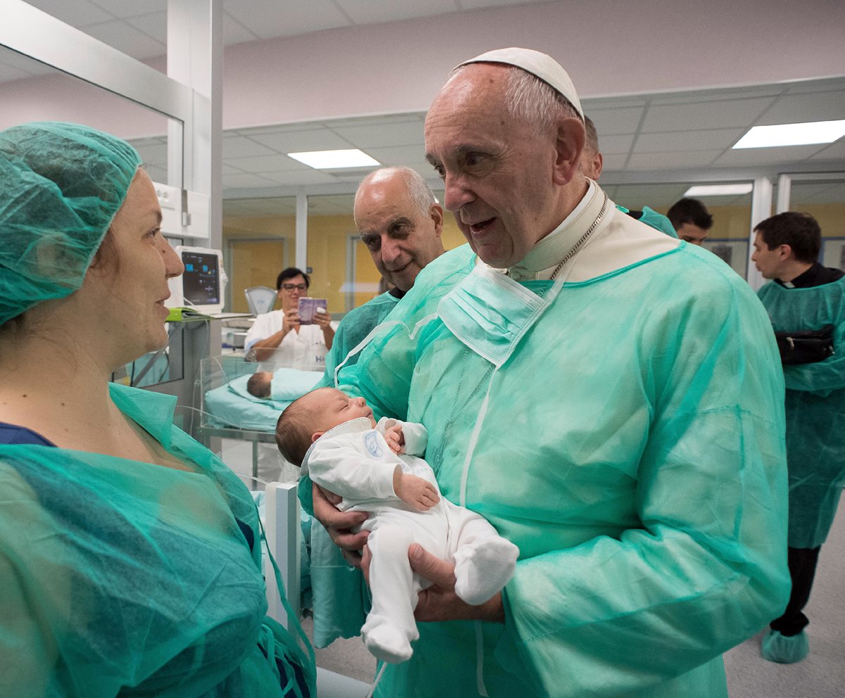 El papa Francisco carga a un recién nacido enfermo durante su visita sorpresa a un hospital en Roma. (Foto Prensa Libre: AP).