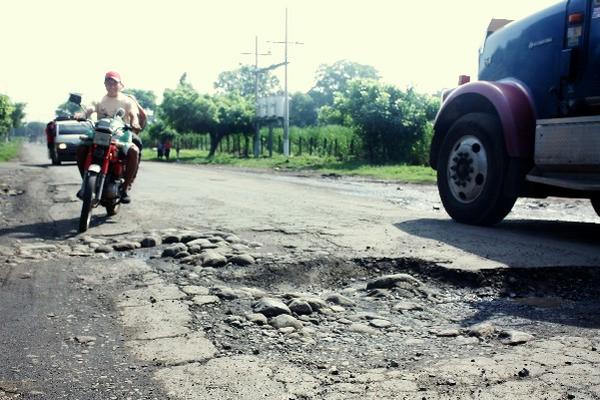 Un motociclista esquiva   los baches en el  tramo  entre  Cuyotenango y  Tiquisate.