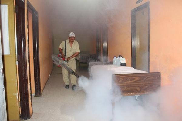 Empleado de Salud fumiga un área del Hospital Regional de San Benito, Petén, con el objetivo de combatir el dengue y ante la alerta del nuevo virus. (Foto Prensa Libre: Rigoberto Escobar)