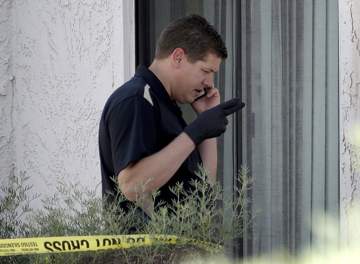 Un oficial de la Policía de Phoenix, durante una diligencia en la vivienda donde ocurrió el macabro crimen. (Foto Prensa Libre: AP).