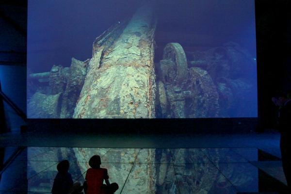 Dos niños miran una proyección con imágenes de los restos del naufragio del Titanic en el fondo del mar, en el centro de Belfast. (Foto Prensa Libre: AFP)