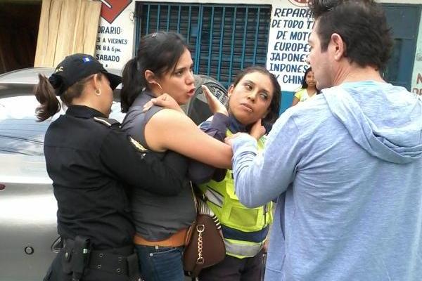 Agente de la PNC sostiene a conductora ebria. (Foto Prensa Libre: PMT de Villa Nueva)