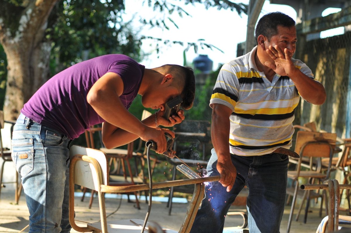 Estudiantes y maestros del Instituto Nacional de Educación Básica, del área urbana de Sayaxché, restauran los pupitres. (Foto Prensa Libre: Rigoberto Escobar)
