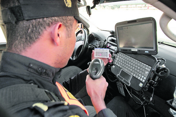 Un agente de la PNC verifica la situación legal de un conductor, mediante el escaneo de   una licencia de conducir. (Foto Prensa Libre: Álvaro Interiano)