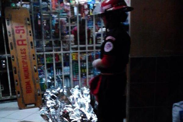 Un bombero Municipal cubre el cadáver del joven muerto a balazos en Villas del Milagro, zona 6 de Mixco. (Foto Prensa Libre: CBM de Mixco)