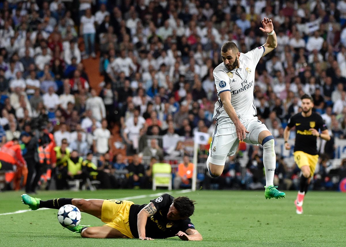Stefan Savic se barre bien a la pelota frente al francés Karim Benzema que salta para evitar el contacto.