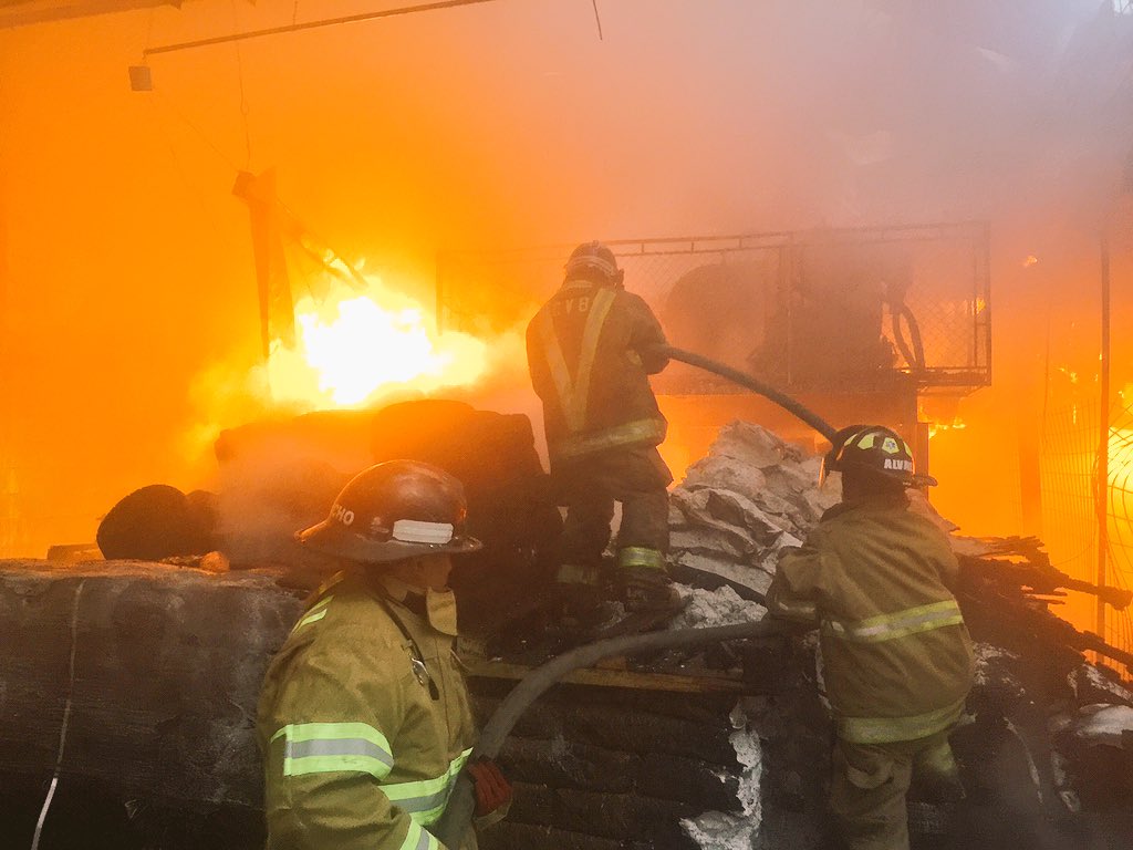 Bomberos Voluntarios combaten las llamas en el interior de la bodega de calzado, en la zona 12. (Foto Prensa Libre: CVB)