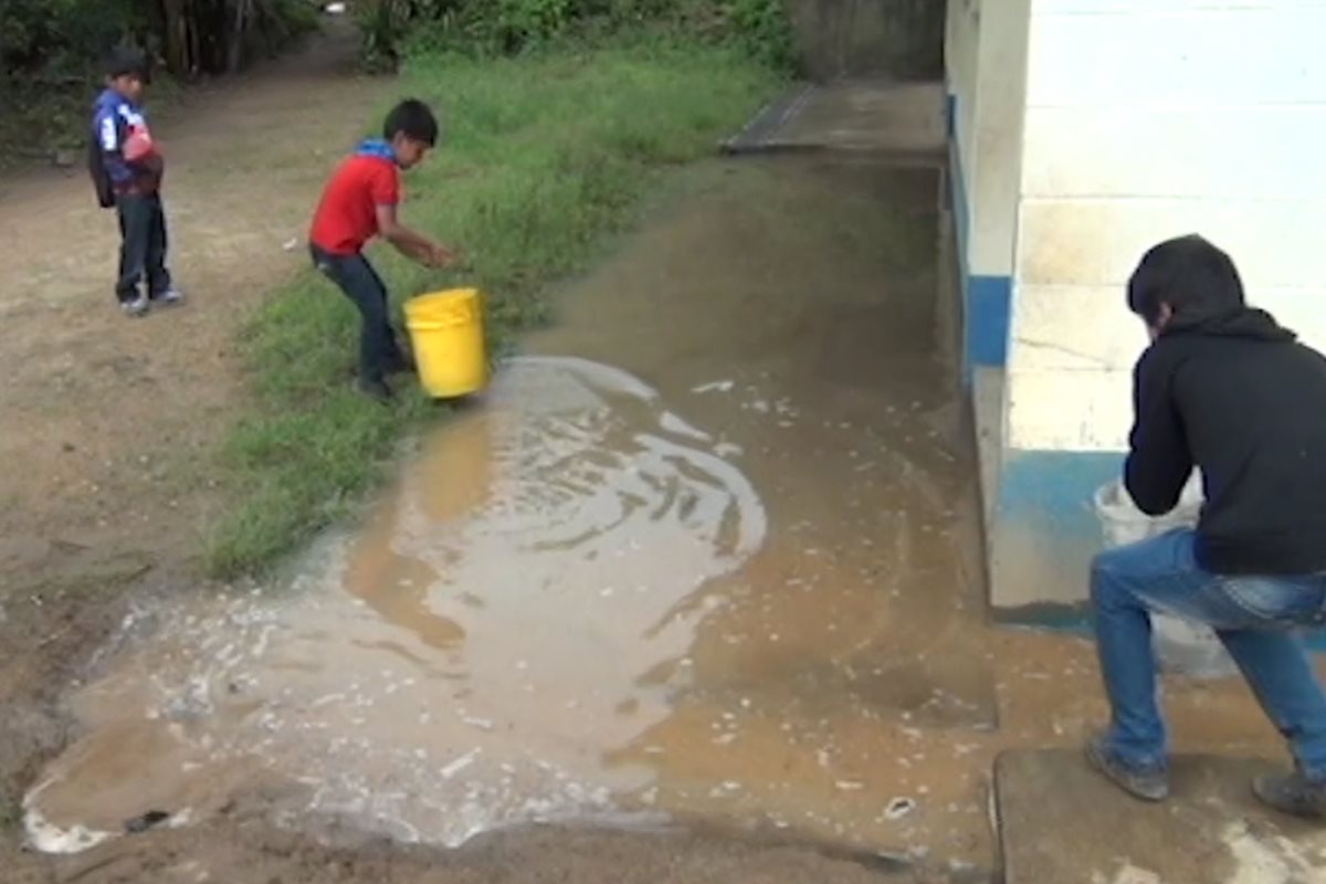 Un estudiante ayuda a sacar el agua reposada en la escuela del caserío Ixquihuilá, San Marcos. (Foto Prensa Libre: Whitmer Barrera)