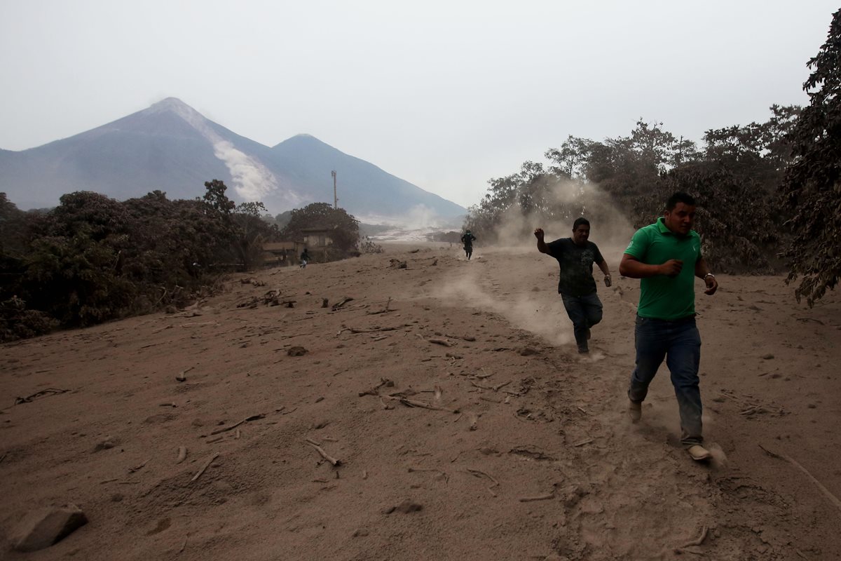 Socorristas y voluntarios corren por un deslizamiento de fluido del volcán de Fuego este lunes. (Foto Prensa Libre: EFE)