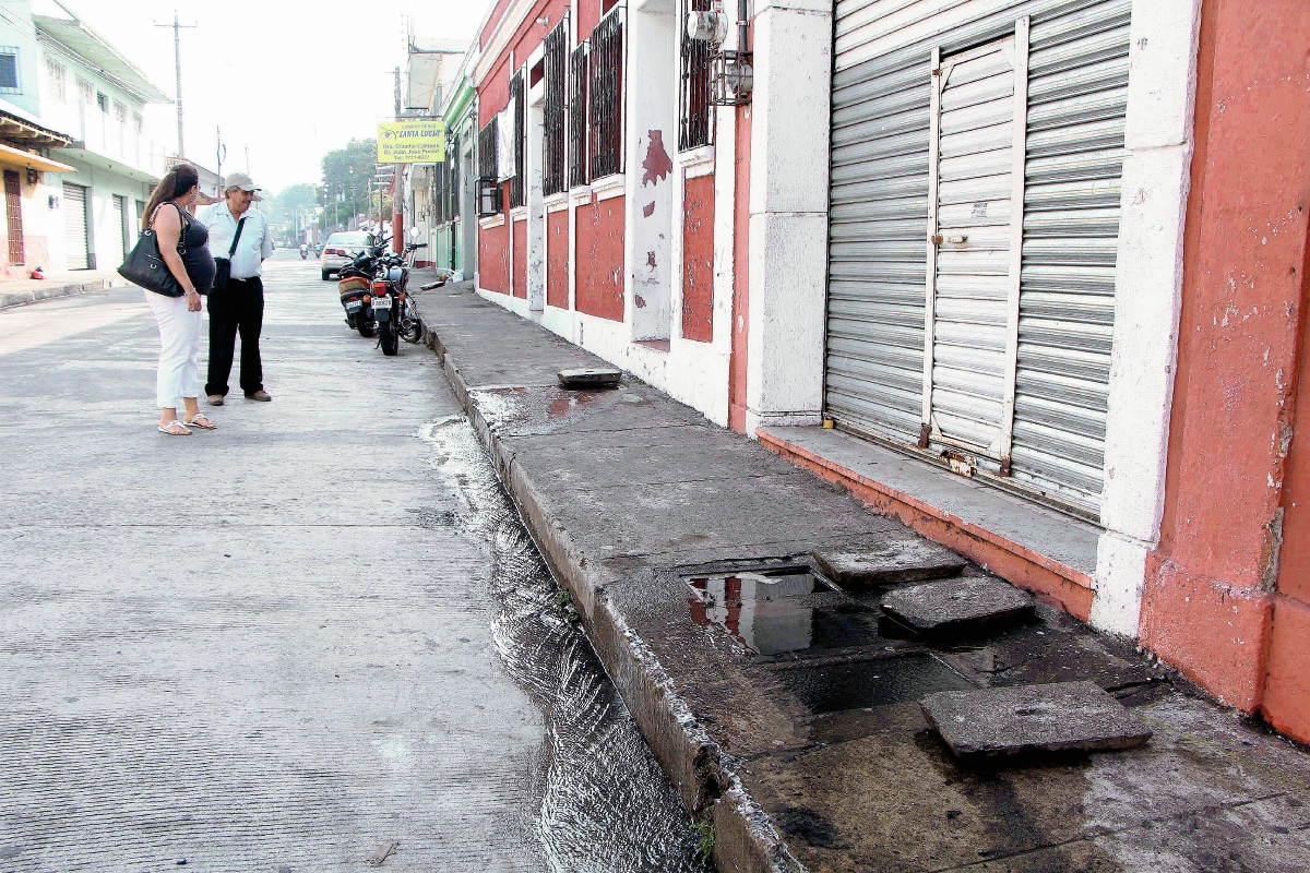 Vecinos verifican  las cajas de cemento en  donde estaban ubicados los medidores de agua. (Foto Prensa Libre: Rolando Miranda)