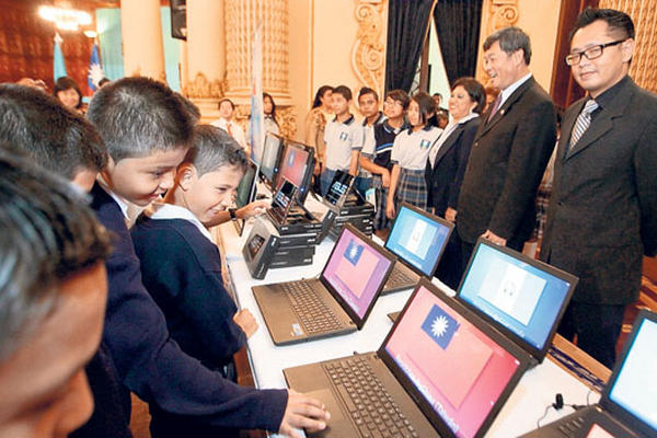 El embajador de Taiwán, Adolfo Sun (centro), invita a niños a que observen las computadoras que donó para escuelas.