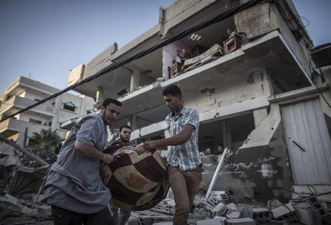 Varios palestinos se llevan objetos rescatados de entre los escombros de una casa destruida por un ataque aéreo nocturno del Ejército israelí en la ciudad de Gaza (Foto Prensa Libre: EFE)