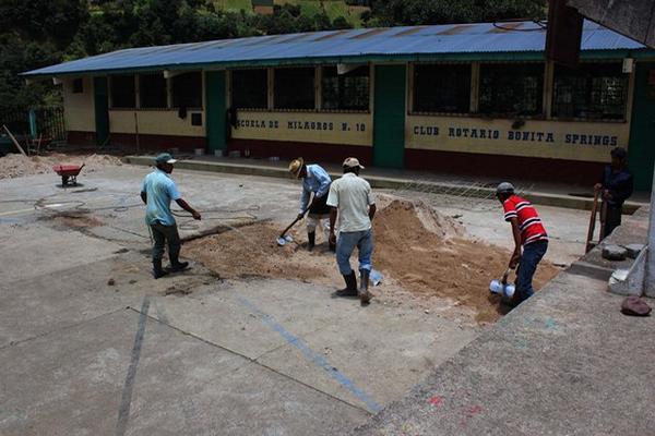 Padres de familia rellenan uno de los agujeros, en la cancha polideportiva de la escuela. (Foto Prensa Libre: José Rosales)
