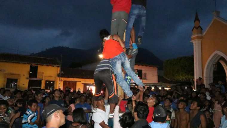 Un grupo de jóvenes hacen el intento de alcanza la bandera roja al final del palo. (Foto Prensa Libre: Renato Melgar)