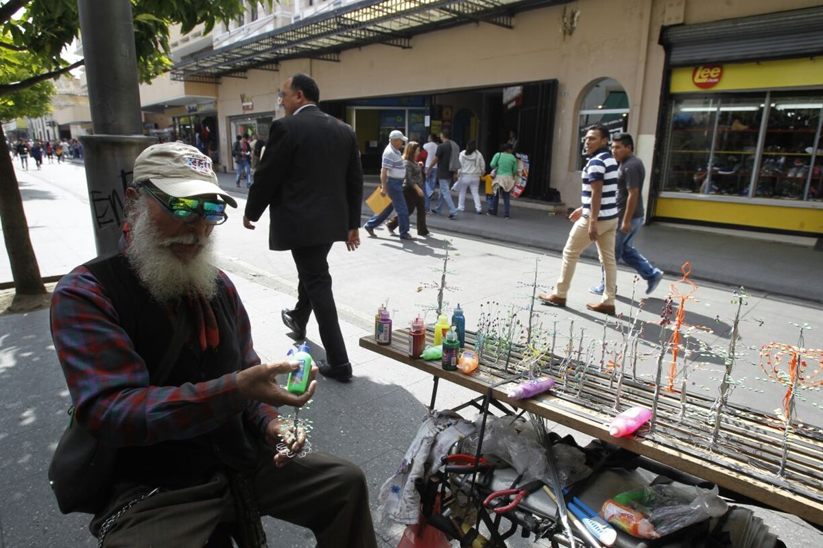 Un anciano elabora artículos con alambre de colores que luego ofrece a peatones en el Paseo de La Sexta. (Foto Prensa Libre: Paulo Raquec)