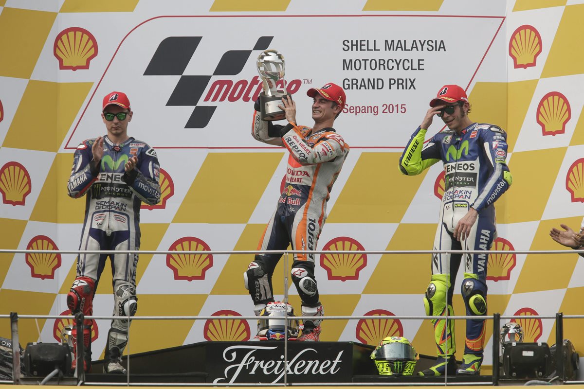 Dani Pedrosa levanta el trofeo en el podio junto a Jorge Lorenzo y Valentino Rossi. (Foto Prensa Libre: EFE)