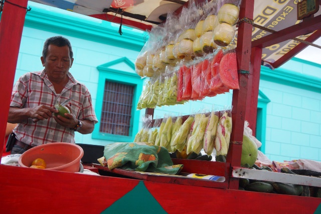 Francisco Méndez prepara mangos que comprarán estudiantes de una escuela cuando salgan de clases. (Foto Prensa Libre: Mario Morales)