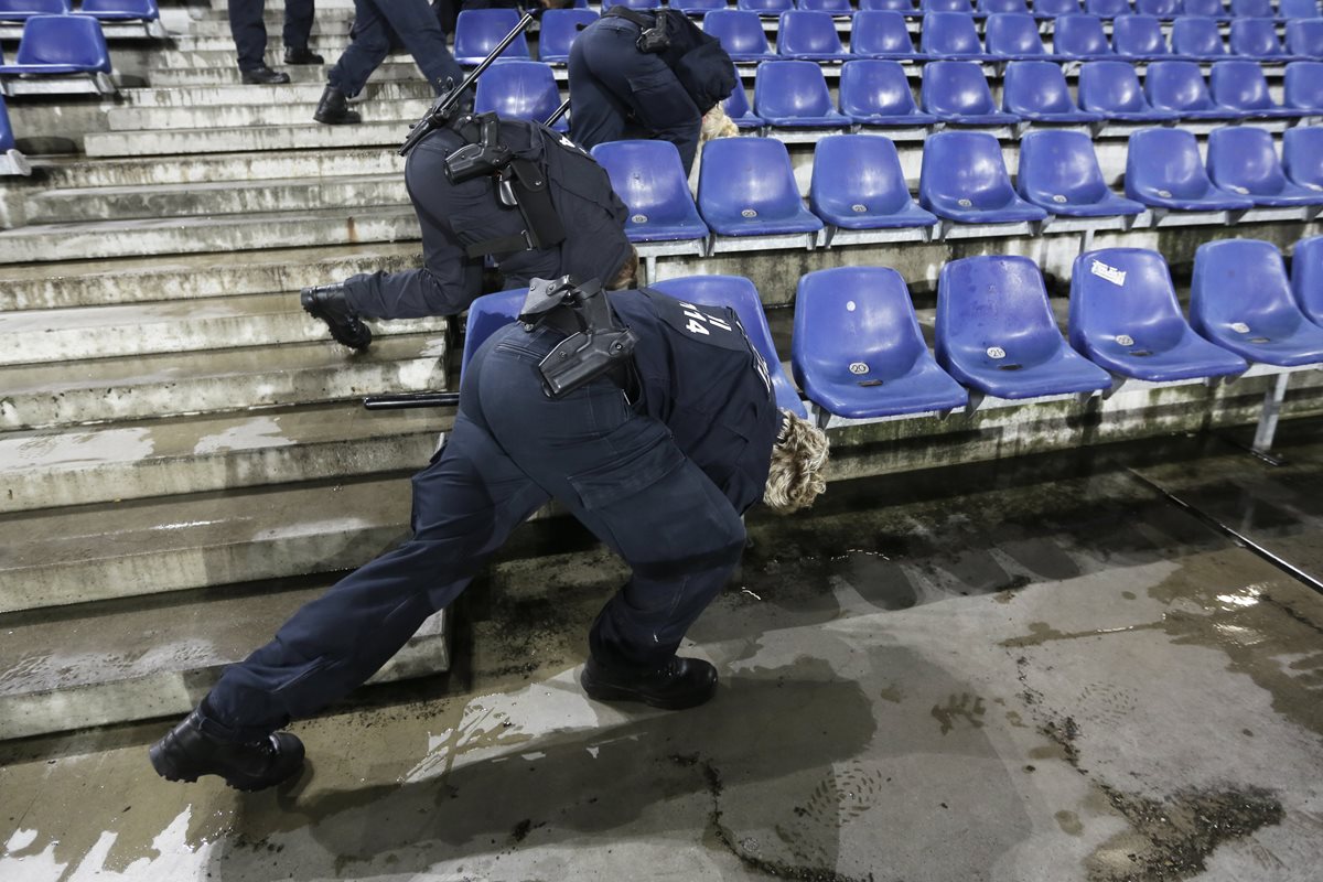 Agentes de la policia alemana revisan abajo de las butacas del estadio de Hannover en busca de algún artefacto explosivo. (Foto Prensa Libre: AP)