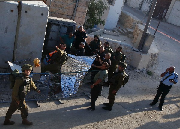 Soldados israelíes cubren el cuerpo de un palestino que murió tras atacar a uno de ellos. (Foto Prensa Libre: AFP)