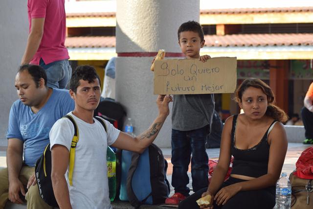 Una familias que acompaña el viacrucis del migrante muestra un rótulo que pide un futuro mejor. (Foto Prensa Libre: EFE)