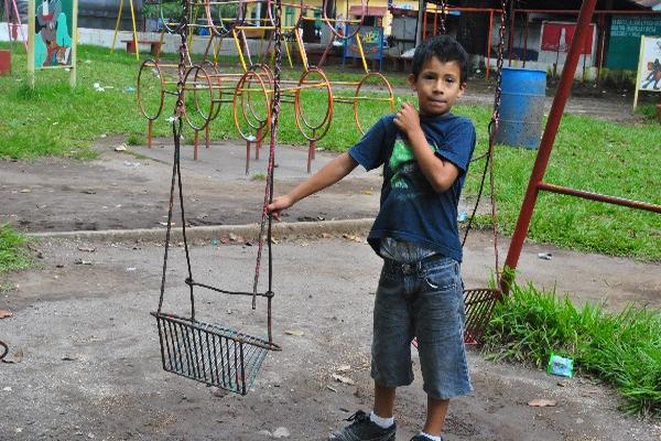 Uno de los niños que llegan a jugar al parque  muestra un columpio dañado.
