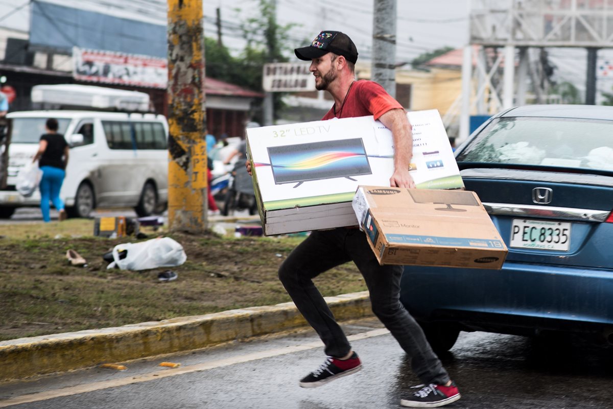 Este hombre corre con un set de televisión luego de participar en un saqueo en San Pedro Sula, Honduras