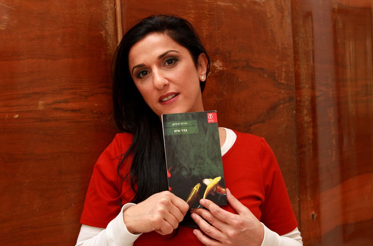 Autora israelí Dorit Rabinyan, con su libro vetado por el gobierno de su país "Gader Haya", ("Borderlife"). (Foto Prensa Libre: AFP)