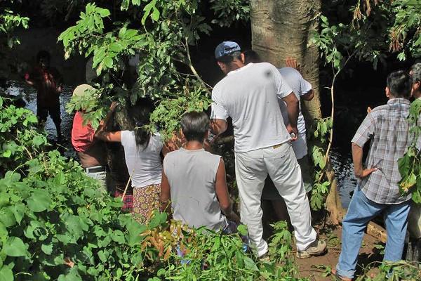 Vecinos observan al pie de un árbol el cadáver de Bartolo López García, en Malacatán.