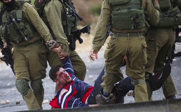 Soldados israelíes transportan a un palestino, herido en un enfrentamiento en Beit El, Ramala.