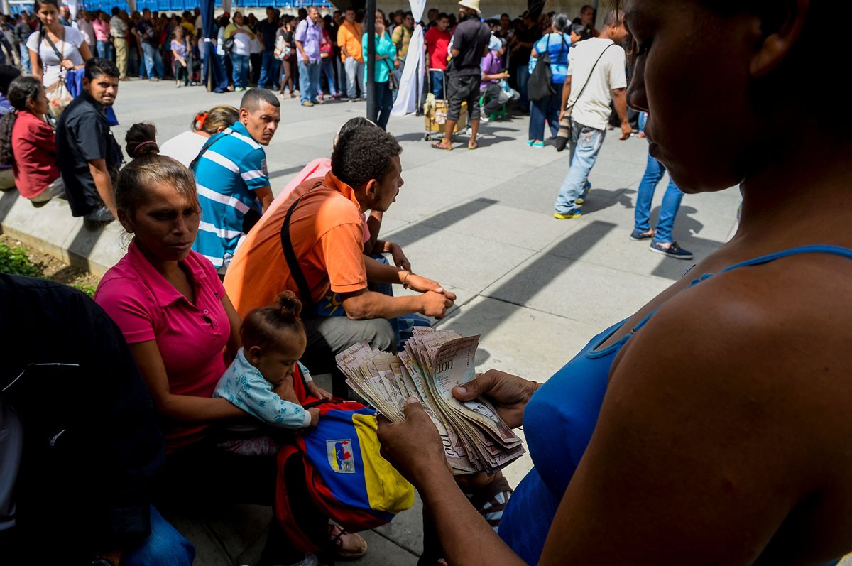 Venezolanos hacen fila en las afueras de una agencia bancaria para cambiar billetes de alta denominación. (Foto Prensa Libre: AFP).