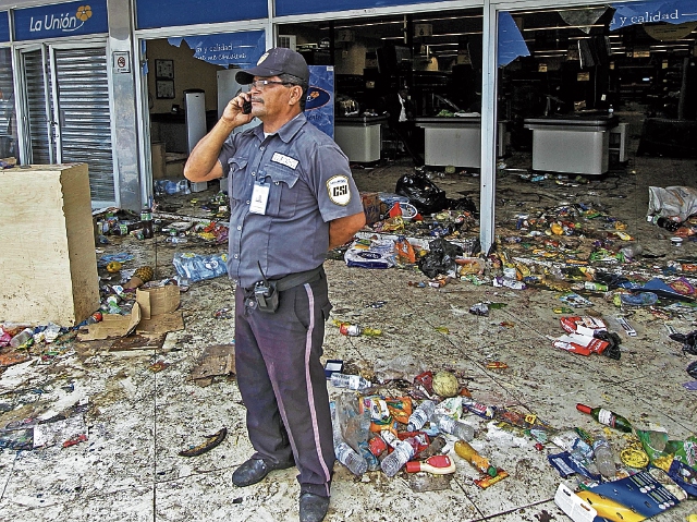 Un guardia de seguridad habla por teléfono tras el saqueo de un local comercial en Nicaragua producto de la ola de protestas contra el presidente Daniel Ortega por cambios en la seguridad social.