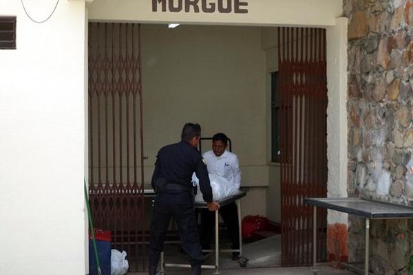 Un agente de la PNC y un empleado de la morgue trasladan el cadáver de un menor que murió baleado, en Jalapa. (Foto Prensa Libre: Hugo Oliva) <br _mce_bogus="1"/>