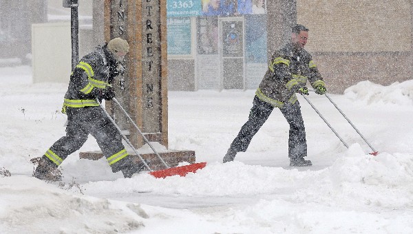 Bomberos limpian la acumulación de nieve frente a una vivienda en Dakota. (Foto Prensa Libre: AP)