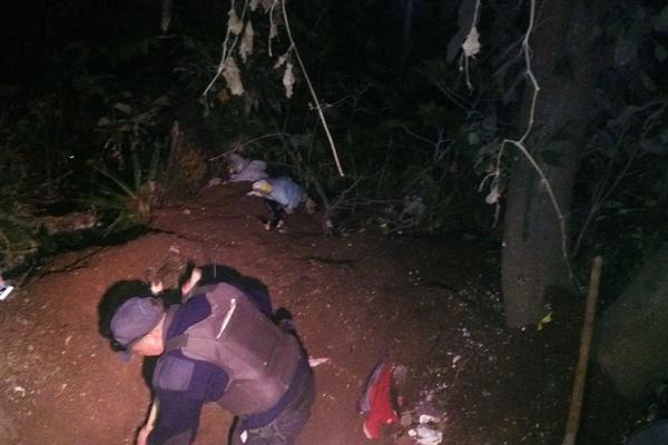 Agentes de la PNC excavan para extraer la sábana que envuelve los restos humanos en La Isla. (Foto Prensa Libre) <br _mce_bogus="1"/>