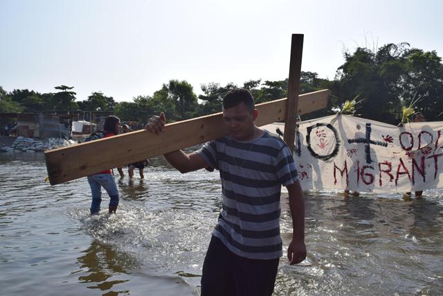 Migrante cruza un río con una cruz en el viacrucis del migrante. (Foto Prensa Libre: EFE)